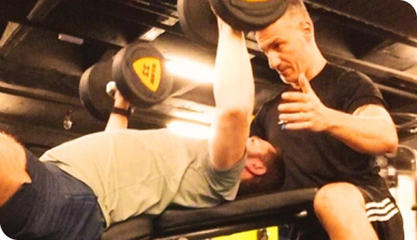 Douglas ajudando aluno com exercícios de halteres